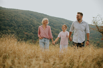 Family enjoying a walk together in a grassy field during a sunny day surrounded by mountains