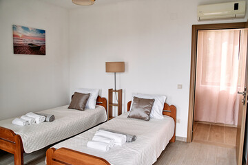 Bright and Cozy Guest Room Featuring Two Twin Beds with Soft Bedding, Well-Lit Space, Elegant Decor, and Inviting Atmosphere for a Relaxing Stay