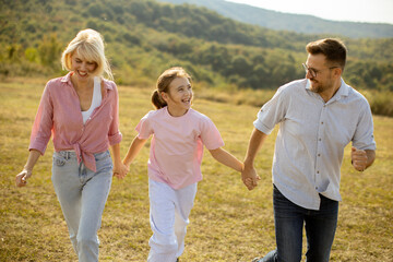 Family enjoys a cheerful afternoon walk in a sunny meadow surrounded by green hills