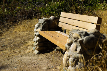 Outdoor Bench Made of Wood and Stone Nestled in a Serene Natural Setting During the Daytime
