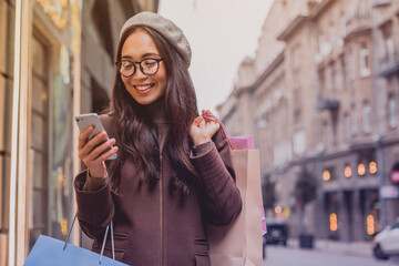 Shopping, bag and happy woman with phone in city street with mall sale news, offer and credit score...