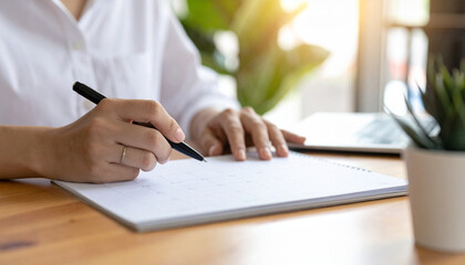 Close-up of man hand writing on calendar planner to organize schedule and plan 2025 business events at modern office desk