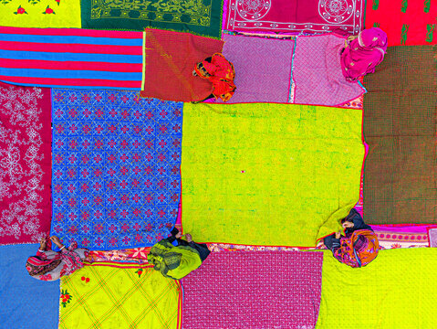 Joypurhat, Bangladesh - 15 October 2022: Aerial view of a vibrant patchwork of colorful fabrics laid out under the open sky, displaying a rich tapestry of textures and patterns.