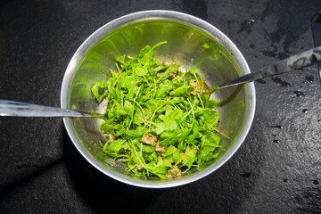 Preparing food at own kitchen with top view of arugula salad with mozzarella pieces and chive on an autumn evening. Photo taken October 6th, 2025, Zurich, Switzerland.