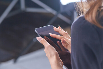 Female with long nails using smartphone indoors in close-up view.