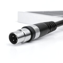Close-up of a four-pin connector cable.  Metallic connector, black cable, white background.  Part of a larger device or box is visible