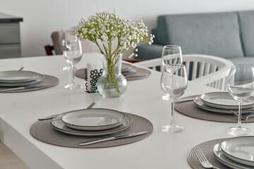 Elegant Dining Table Setting with Fresh Flowers and Tableware for a Sophisticated Dining Experience in a Modern Home Environment