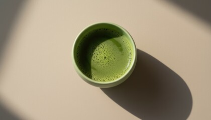 Minimalist top view of green matcha tea cup with sunlight shadow, concept of calm, wellness and Japanese tea culture