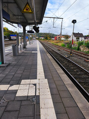 Empty european railway station platform extending into the distance under a cloudy sky
