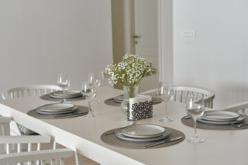 Elegant Dining Table with Glassware and Floral Centerpiece in a Minimalist Setting for Special Occasions or Casual Gatherings