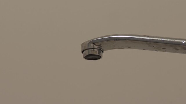 Close-up of water drop dripping from faucet in bathroom, plumbing system malfunction at home, water leakage from dripping tap