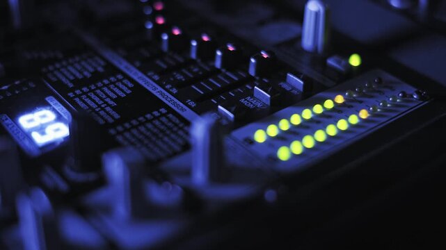 Close-up dolly shot moving toward professional audio console, showing pulsing green LED level meters, blue digital readout, and multi-effects processor text in dark music studio or broadcast booth.