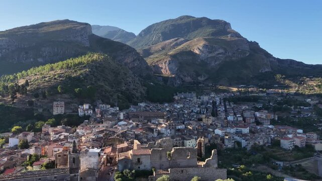 Aerial drone view of Collesano Sicilian mountain town at sunset with Basilica San Pietro church and historic stone streets in the Madonie Mountains, Sicily, Italy. Old mountain town in Sicily