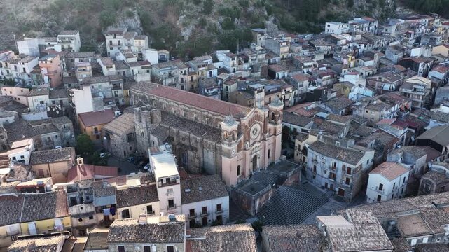 Aerial drone view of Collesano Sicilian mountain town at sunset with Basilica San Pietro church and historic stone streets in the Madonie Mountains, Sicily, Italy. Old mountain town in Sicily