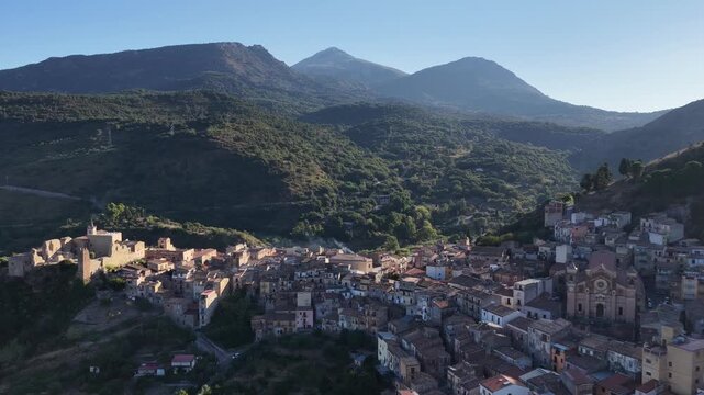 Aerial drone view of Collesano Sicilian mountain town at sunset with Basilica San Pietro church and historic stone streets in the Madonie Mountains, Sicily, Italy. Old mountain town in Sicily