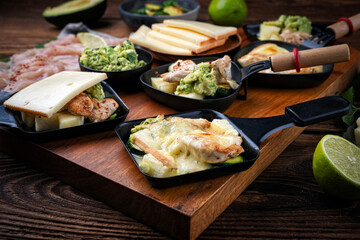 Traditional authentic swiss raclette with chicken filet meat, pineapple, avocado and savoy cheese served as close-up on wooden design board