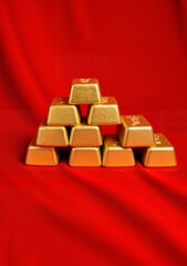 Gold bullion bars arranged in a pyramid on red background for Lunar New Year  