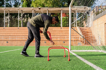 Coach arranging hurdles along a goal