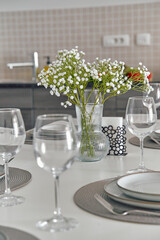 Elegant Table Setting with Delicate Flowers and Glassware for a Modern Dining Experience