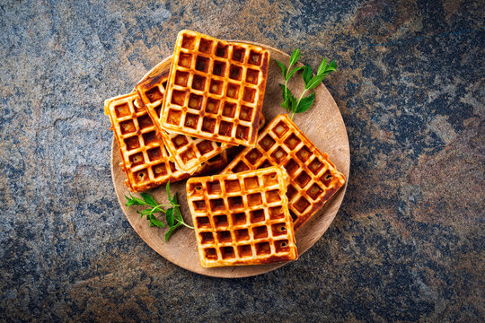 Traditional fresh baked homemade Brussels waffles served as close-up on a rustic wooden board