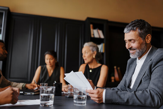 Senior lawyer smiling and reading documents during a meeting