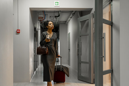Businesswoman with Luggage Walking Through Hotel Corridor