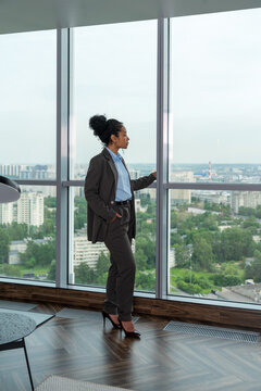 Businesswoman Looking Out Hotel Window at Cityscape