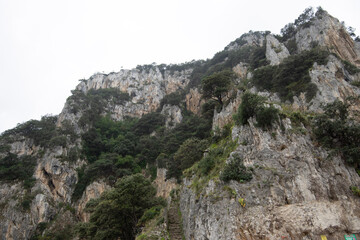 Climbing steep stone steps carved into the rugged cliffside of Punta del Caballo in Santoña, Cantabria, Spain, offering an active and adventurous ascent for hikers and tourists