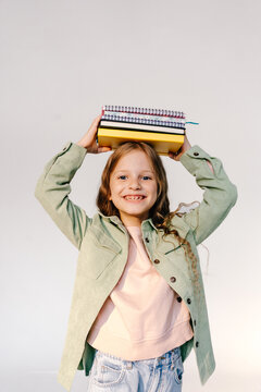 Schoolgirl with stack of notebooks on head