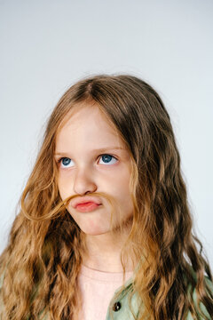 Female kid creating fake mustache with hair