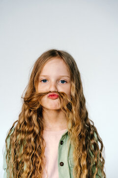 Playful girl making mustache with hair