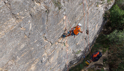 Man smiling and giving thumbs up while abseiling down a rock cliff in Sant Joan de Mediona, Spain, feeling freedom and adventurous during sport climbing