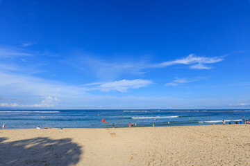 Beach with people swimming in the ocean and a clear blue sky