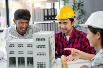 Architects and engineers collaborating on a sustainable construction project, reviewing building model with a wind energy component