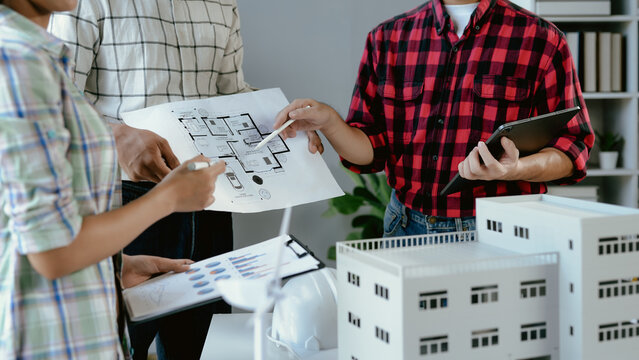 Architects team meeting in office, analyzing floor plan, discussing building model, and collaborating on new engineering project