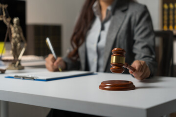 Female lawyer making judgment, holding a gavel at desk, representing justice, law, and legal...