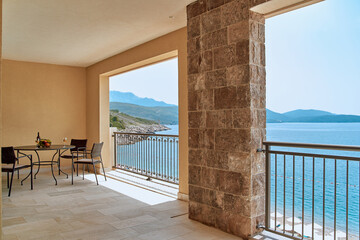 A Serene Coastal Retreat Featuring a Beautiful Terrace Overlooking Crystal-Clear Waters and Majestic Mountains in the Background