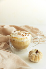 Cozy pumpkin latte with whipped cream and spices, surrounded by autumn decor.