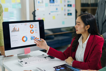 Professional businesswoman analyzing financial charts and graphs on a computer monitor during a corporate business presentation