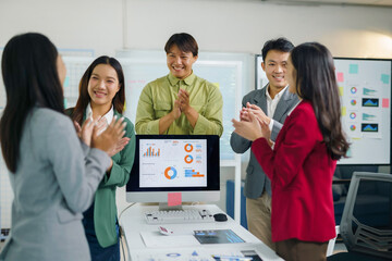 Asian business team members applauding a successful presentation during an office meeting, celebrating project achievement