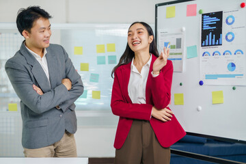 Asian business people collaborating, discussing strategy and sharing ideas at a whiteboard in a modern office