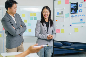 Asian business professionals discussing ideas and analyzing data charts during an office meeting, focusing on business growth