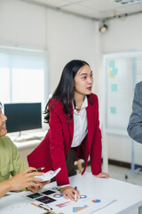 Professional Asian business woman presenting financial charts and data during a team meeting in a modern office