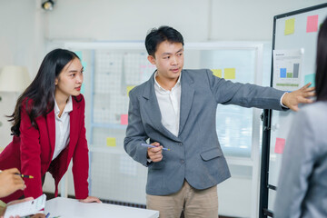 Young Asian professionals discussing marketing strategy, sharing ideas during a business meeting in a modern office