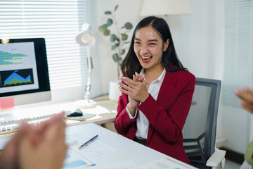 Happy businesswoman clapping hands, celebrating success and teamwork during an office meeting with colleagues