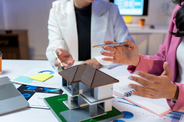 Professional real estate agents brainstorming house project while planning home investment with architectural model and documents