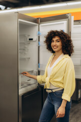Smiling Woman Examining Modern Refrigerator in Appliance Store