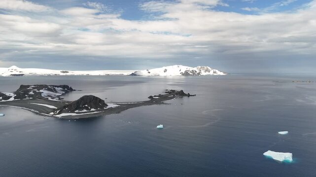 Experience Antarctica's breathtaking landscape as large icebergs drift through calm waters near towering snow-capped peaks.