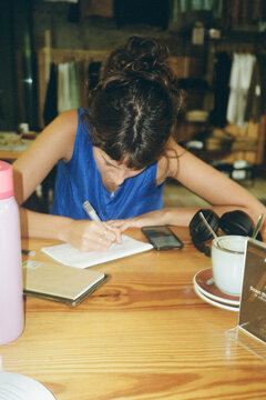 young woman wring in her journal in Caf&eacute;