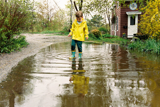 Child walks through rain puddle